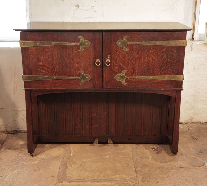 A 1904, Broadwood 'Manxman' piano with an Arts and Crafts, oak case, wrought steel sconces and brass strap hinges. Designed by M. H. Baillie Scott. Piano has an eighty-five note keyboard and two pedals.