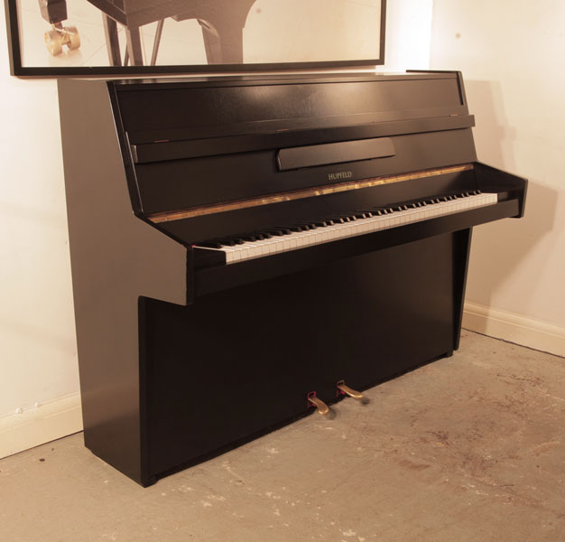 Reconditioned, 1970, Hupfeld  upright piano with a satin, black case and brass fittings . Piano has an eighty-five note keyboard and two pedals